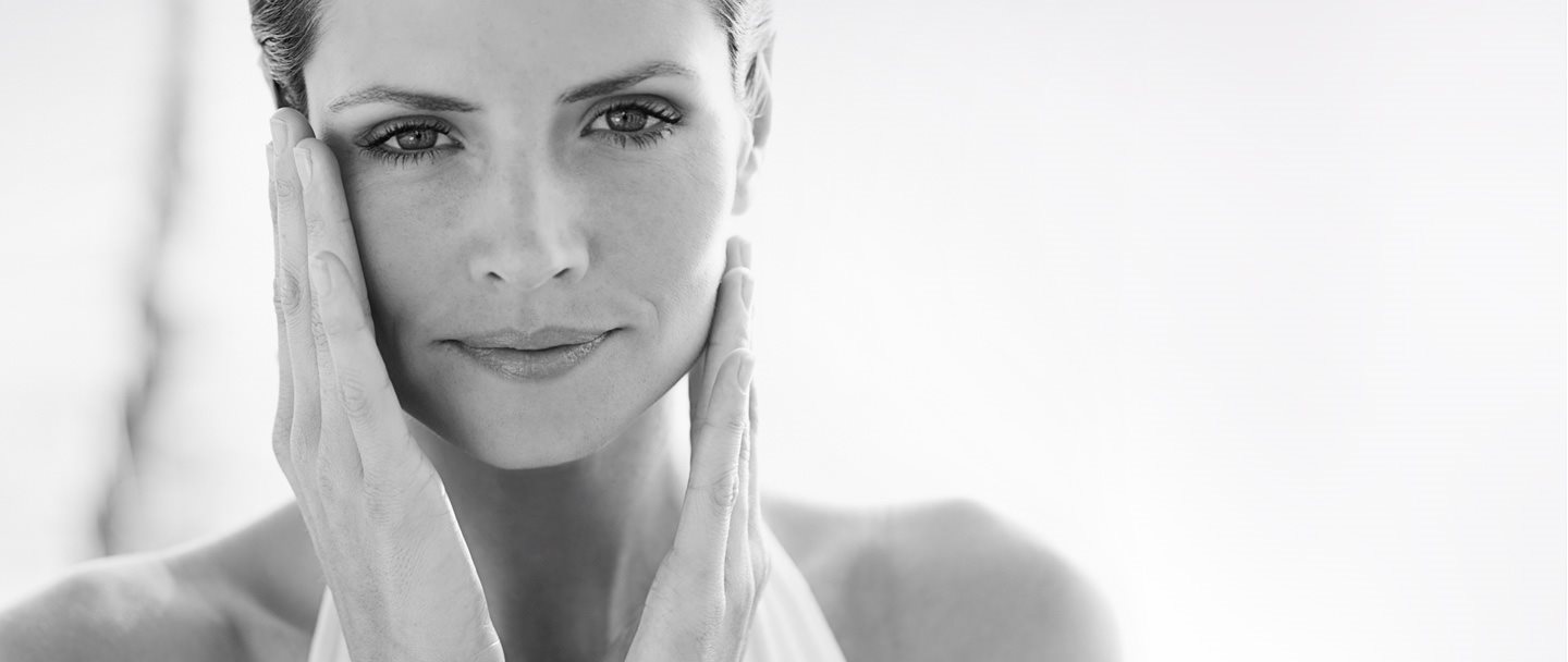 Femme se touchant le visage avec les deux mains.